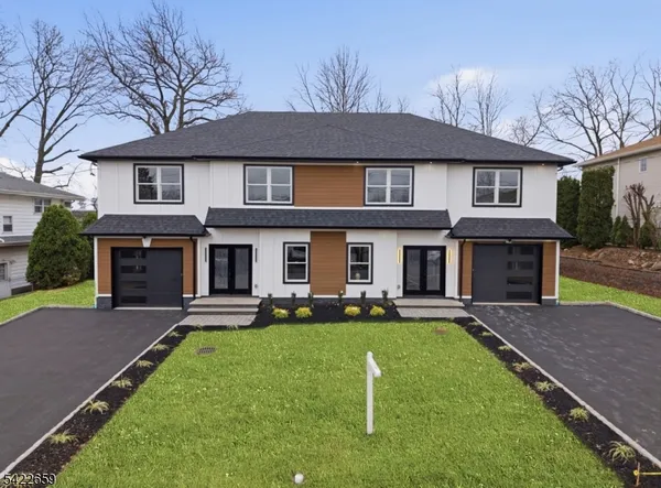 a front view of a house with a yard and trees