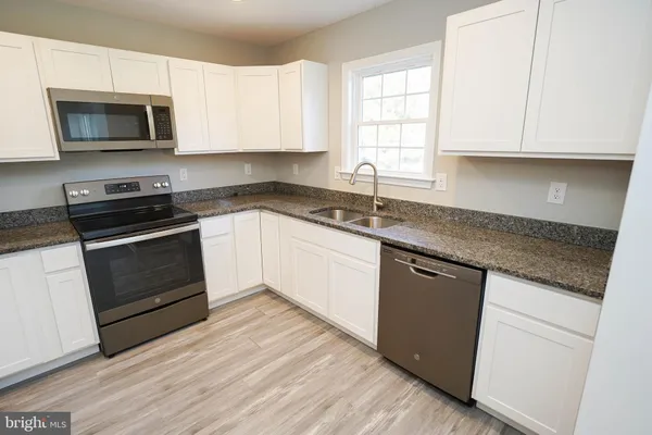 a kitchen with granite countertop white cabinets and white appliances