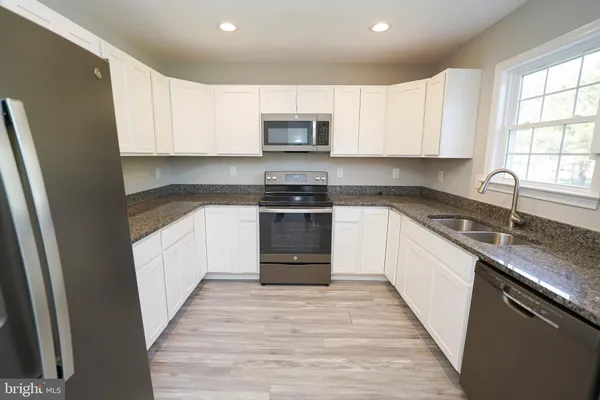 a kitchen with granite countertop a refrigerator stove and microwave
