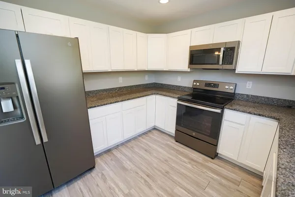 a kitchen with granite countertop white cabinets and refrigerator