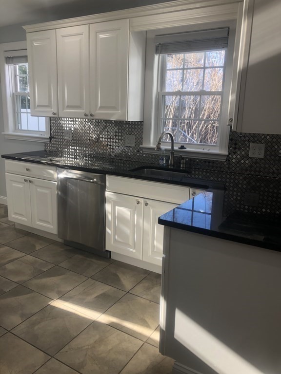 10-12 Tanglewood Road Boston, MA 02126 - Photo 14 of 17 a kitchen with granite countertop a stove a sink and a white cabinets