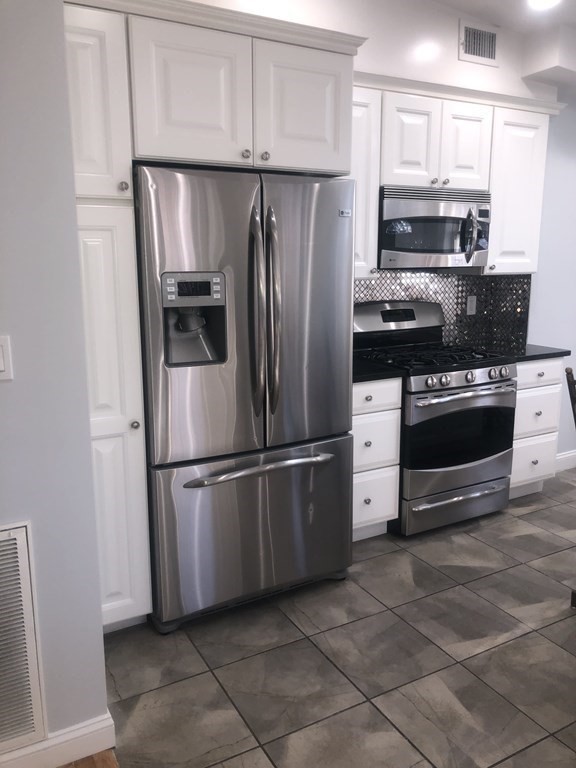 10-12 Tanglewood Road Boston, MA 02126 - Photo 15 of 17 a kitchen with stainless steel appliances a refrigerator stove and microwave