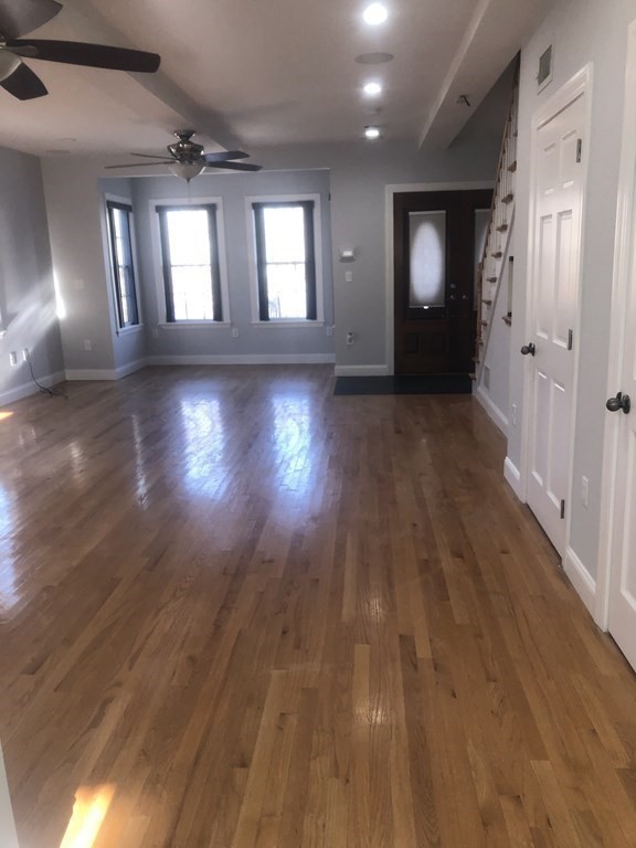 10-12 Tanglewood Road Boston, MA 02126 - Photo 4 of 17 an empty room with wooden floor and windows