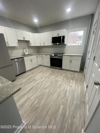 a large kitchen with stainless steel appliances granite countertop a stove a sink and a microwave
