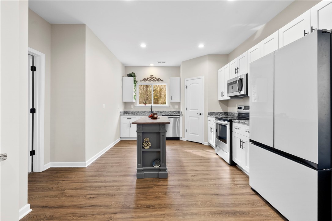 102 Colonial Court Pendleton, SC 29670 - Photo 11 of 30 This bright kitchen features wood flooring and stainless steel appliances, creating a welcoming and functional space.