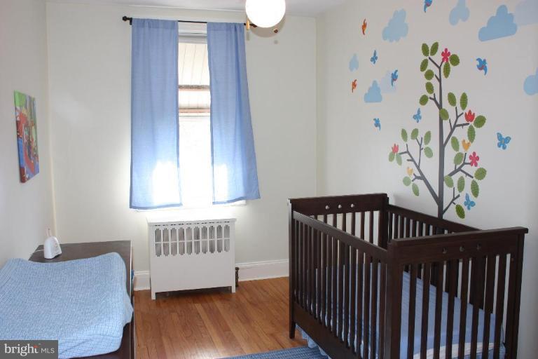 3629 Elkader Road Baltimore, MD 21218 - Photo 7 of 19 a bedroom with a window and wooden floor
