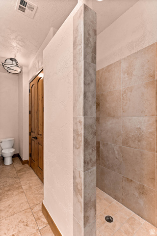 2464 East Granite Way St. George, UT 84790 - Photo 69 of 106 Full bath featuring tiled shower, a textured wall, a textured ceiling, and light tile patterned floors