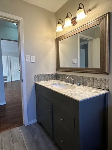 a bathroom with a granite countertop sink vanity and mirror