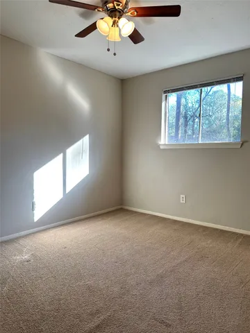 an empty room with a chandelier fan and windows