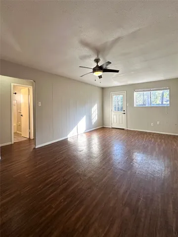 a view of an empty room with wooden floor and a window