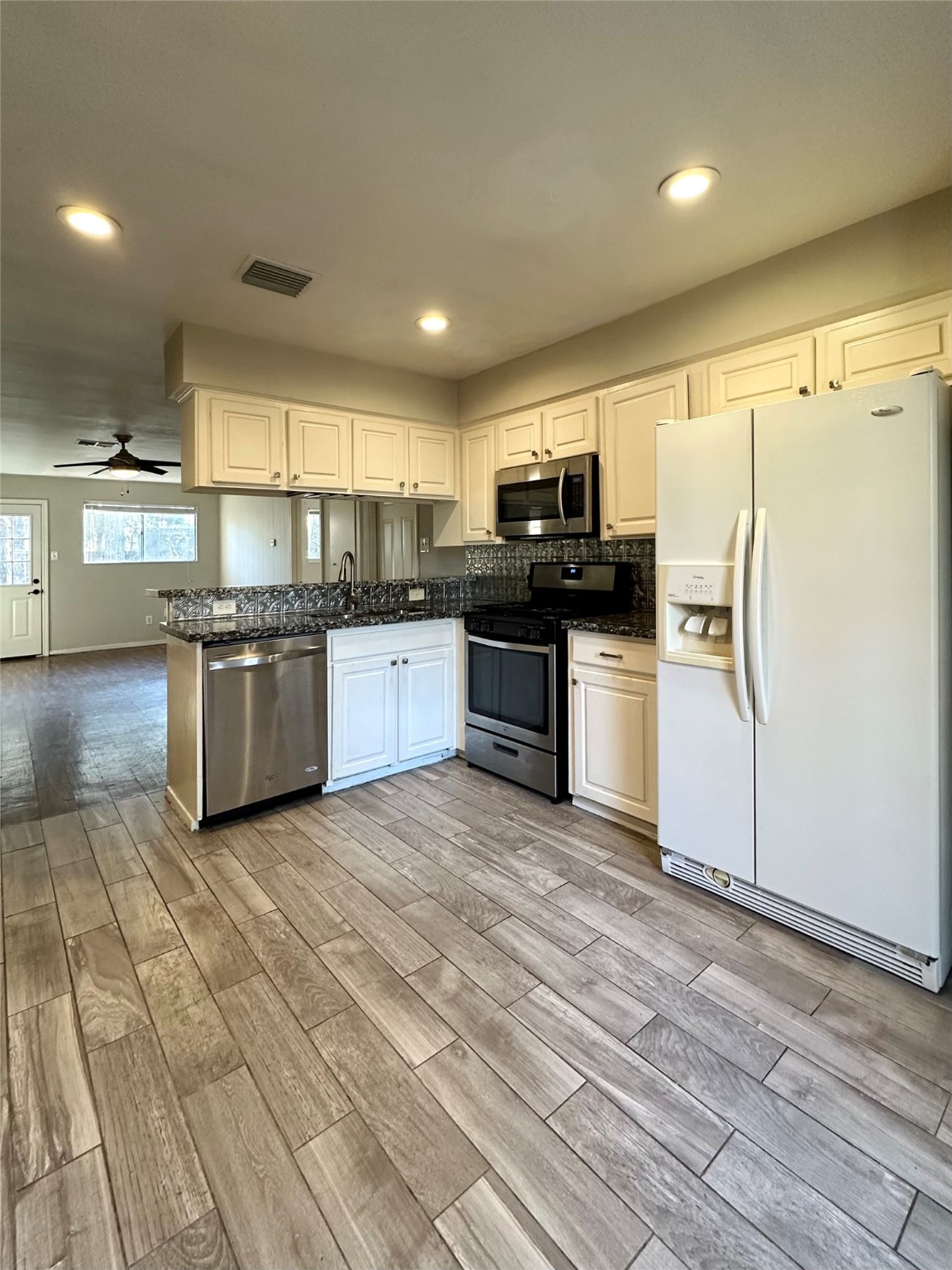 3223 Brooktree Lane Spring, TX 77380 - Photo 5 of 30 a kitchen with stainless steel appliances granite countertop a stove top oven a sink dishwasher a refrigerator and a dining table with wooden floor