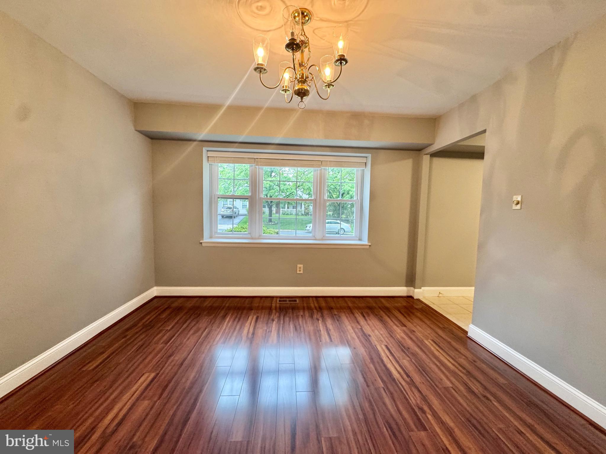 4908 Rocky Spring Lane Bowie, MD 20715 - Photo 7 of 36 an empty room with wooden floor chandelier and windows