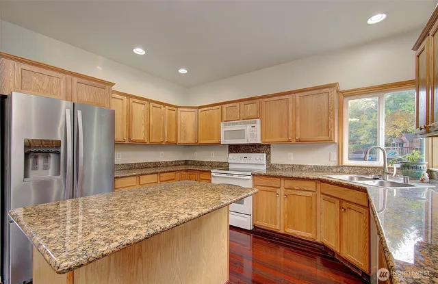 a kitchen with stainless steel appliances granite countertop refrigerator sink and cabinets