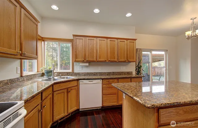 a kitchen with stainless steel appliances granite countertop wooden cabinets a sink and dishwasher with wooden floor