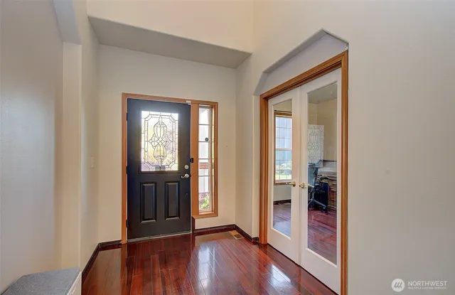 a view of a hallway with wooden floor and a bathroom