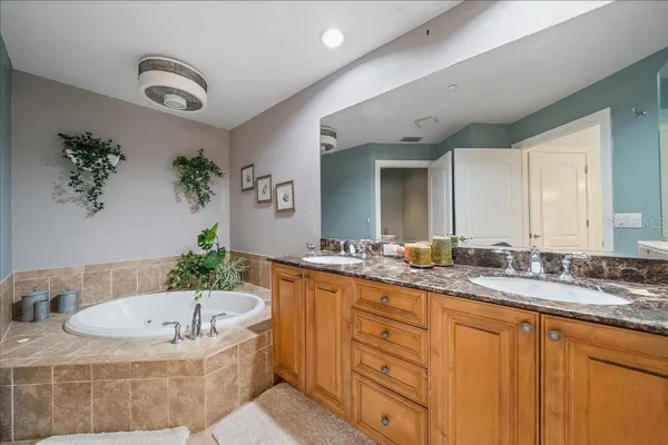 a bathroom with a granite countertop tub sink and mirror