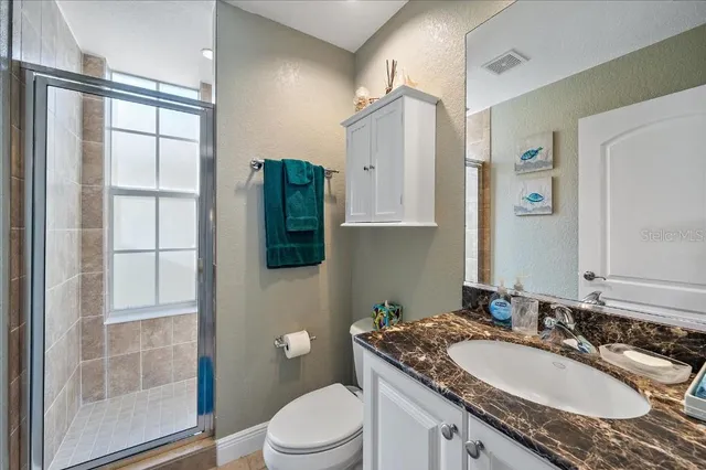 a bathroom with a granite countertop sink a toilet a mirror and shower