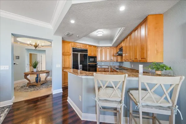 a kitchen with stainless steel appliances kitchen island granite countertop a stove a refrigerator a sink dishwasher and white cabinets with wooden floor