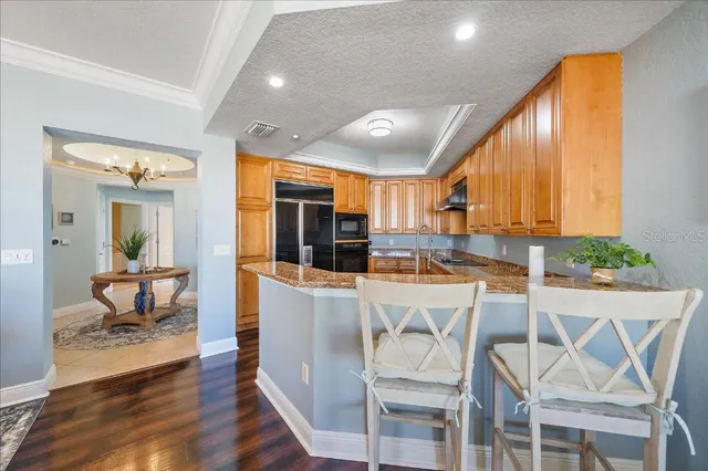 a kitchen with stainless steel appliances kitchen island granite countertop a stove a refrigerator a sink dishwasher and white cabinets with wooden floor