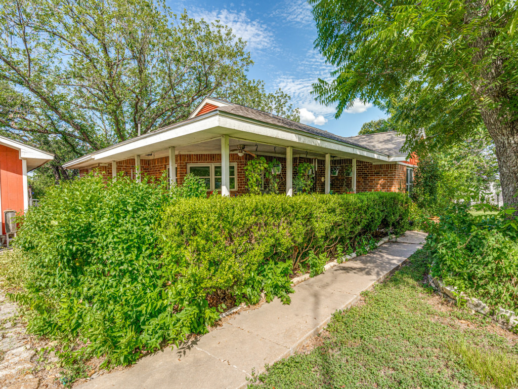 1035 Palomino Road Kyle, TX 78640 - Photo 4 of 13 Mature trees and lush landscaping frame this inviting brick facade with a welcoming covered front porch.