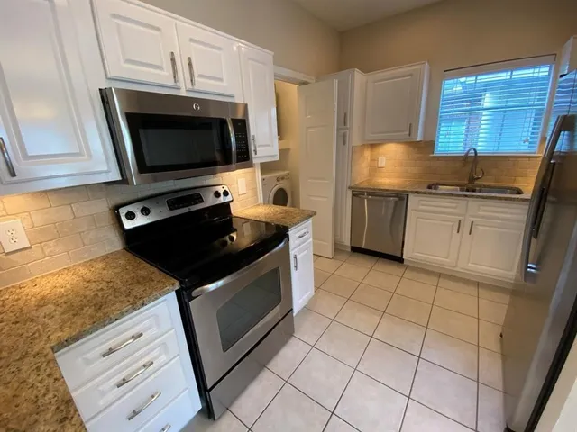 a kitchen with granite countertop a stove a sink and a microwave