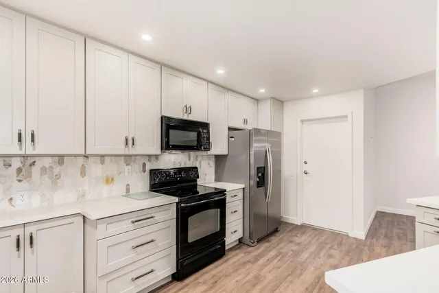 a kitchen with granite countertop white cabinets and stainless steel appliances