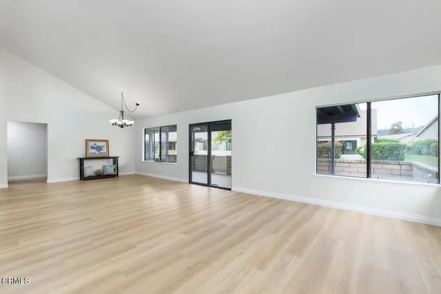 a view of an empty room with a window and a kitchen