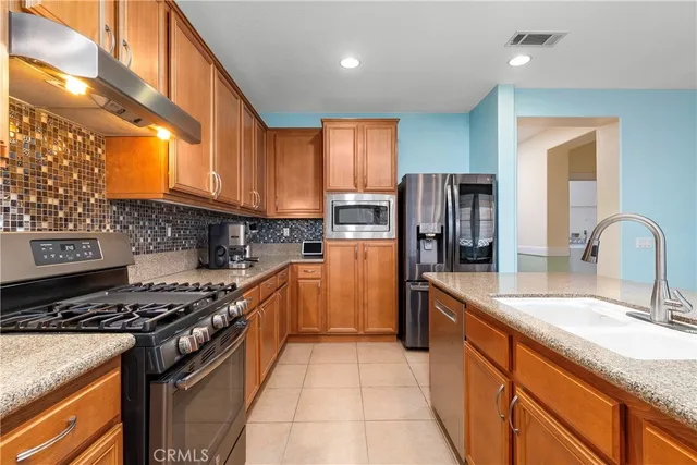 a kitchen with stainless steel appliances granite countertop a stove a sink and a refrigerator
