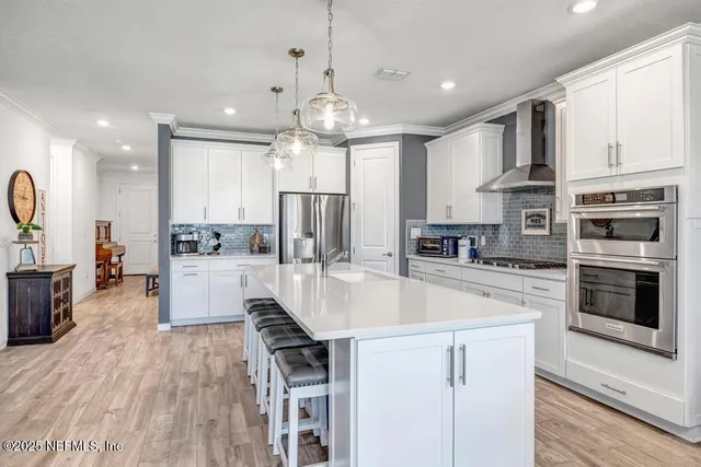 a kitchen with stainless steel appliances kitchen island granite countertop a dining table chairs and white cabinets