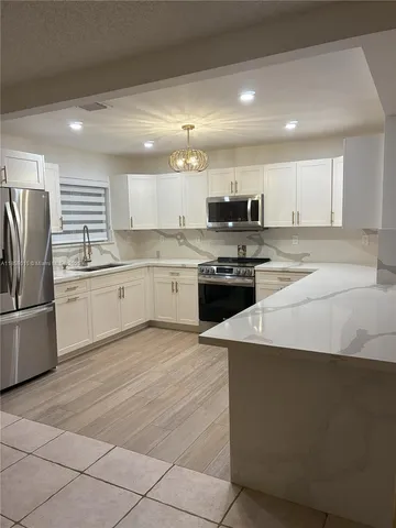 a kitchen with stainless steel appliances granite countertop a stove a sink dishwasher and a refrigerator