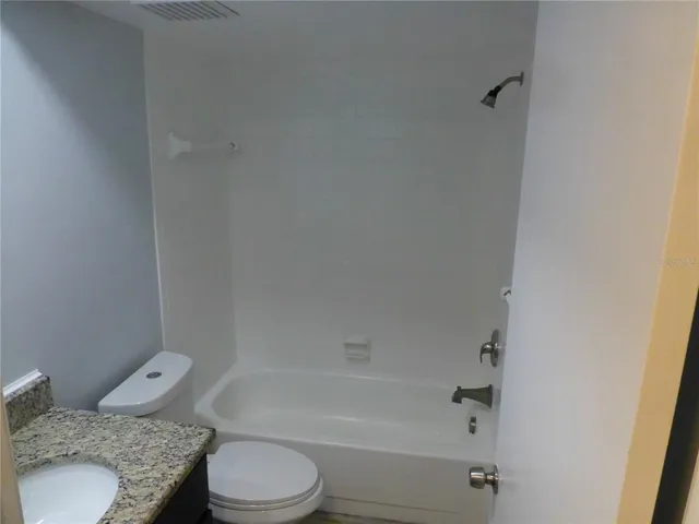 a bathroom with a granite countertop toilet and a bathtub