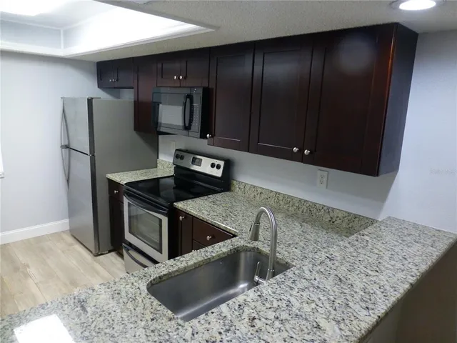 a kitchen with stainless steel appliances granite countertop a refrigerator and a sink
