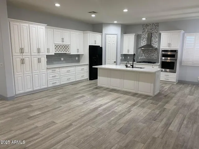 a large kitchen with kitchen island a sink a center island stainless steel appliances and a cabinets