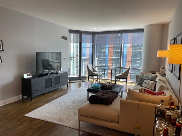 a living room with furniture a flat screen tv and a floor to ceiling window