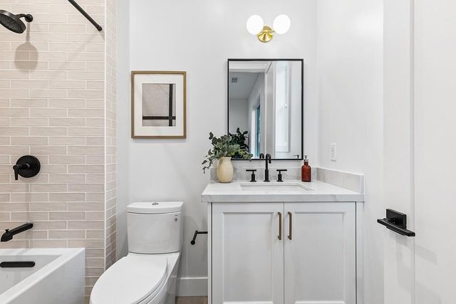 a bathroom with a sink a toilet a mirror a vanity a bath tub and shower