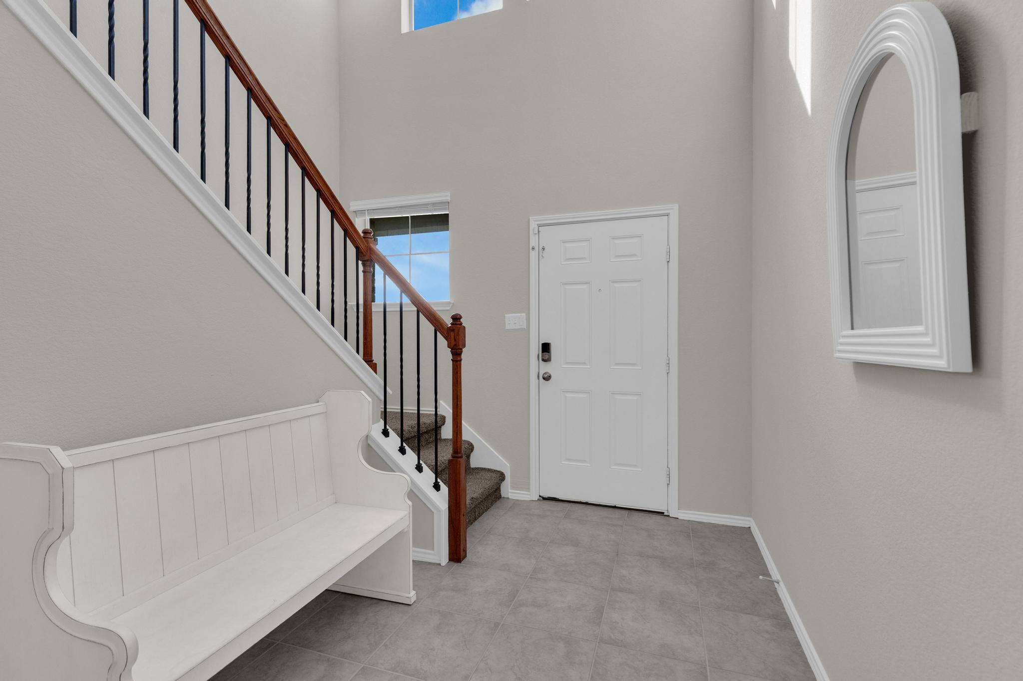 104 Uncle Billy Way Jarrell, TX 76537 - Photo 7 of 38 A graceful staircase with wood and wrought iron balusters ascends from a welcoming foyer with tiled floors.