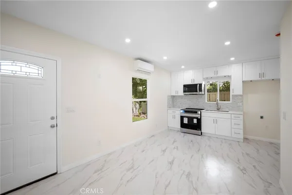 a kitchen with stainless steel appliances granite countertop a refrigerator oven a sink dishwasher and white cabinets with wooden floor