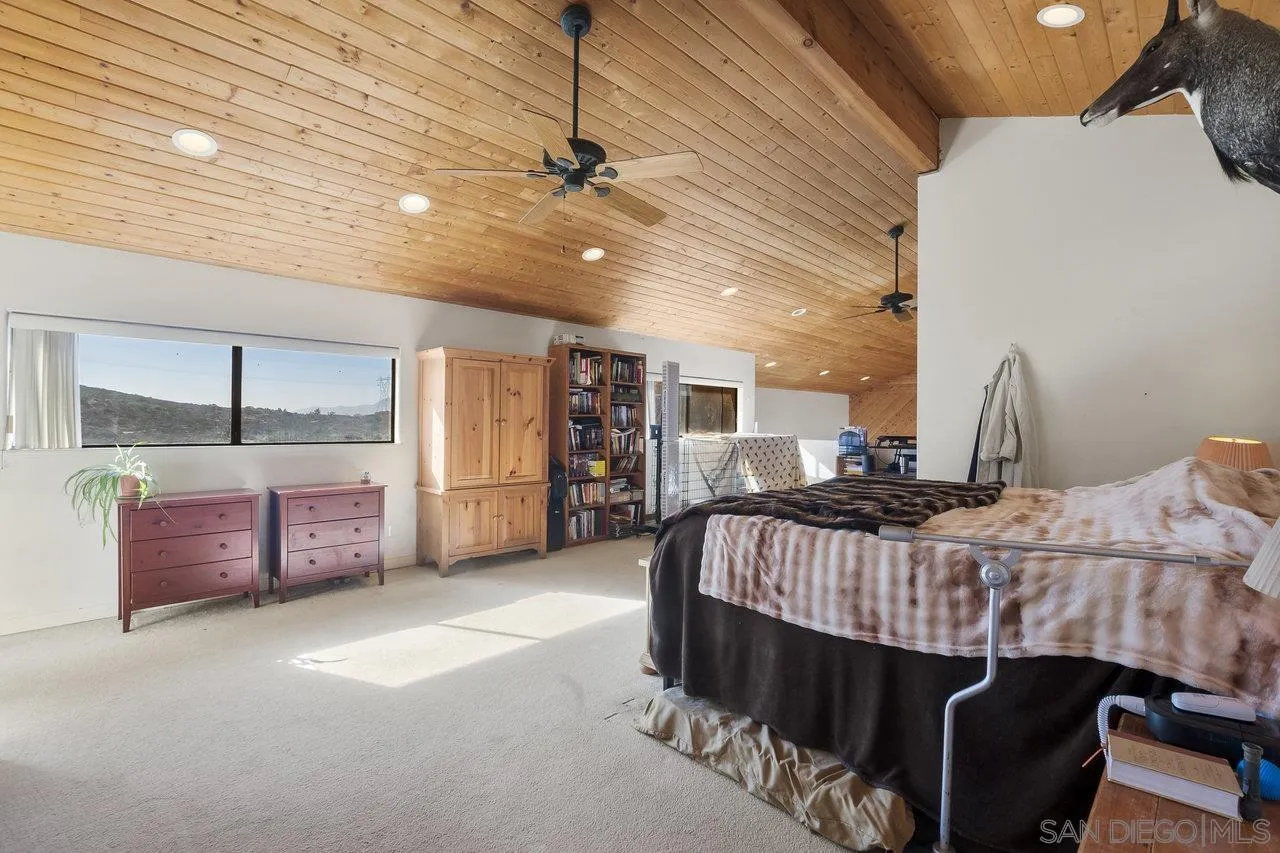18995 Highway 94 Dulzura, CA 91917 - Photo 29 of 55 a bedroom with a bed a chandelier and flat screen tv