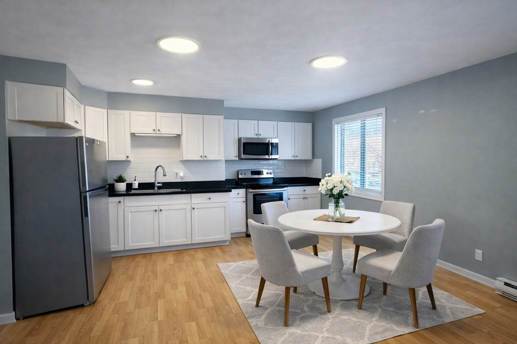 16 Cleveland Place, Unit 11 Gloucester, MA 01930 - Photo 1 of 8 a kitchen with a dining table chairs and refrigerator
