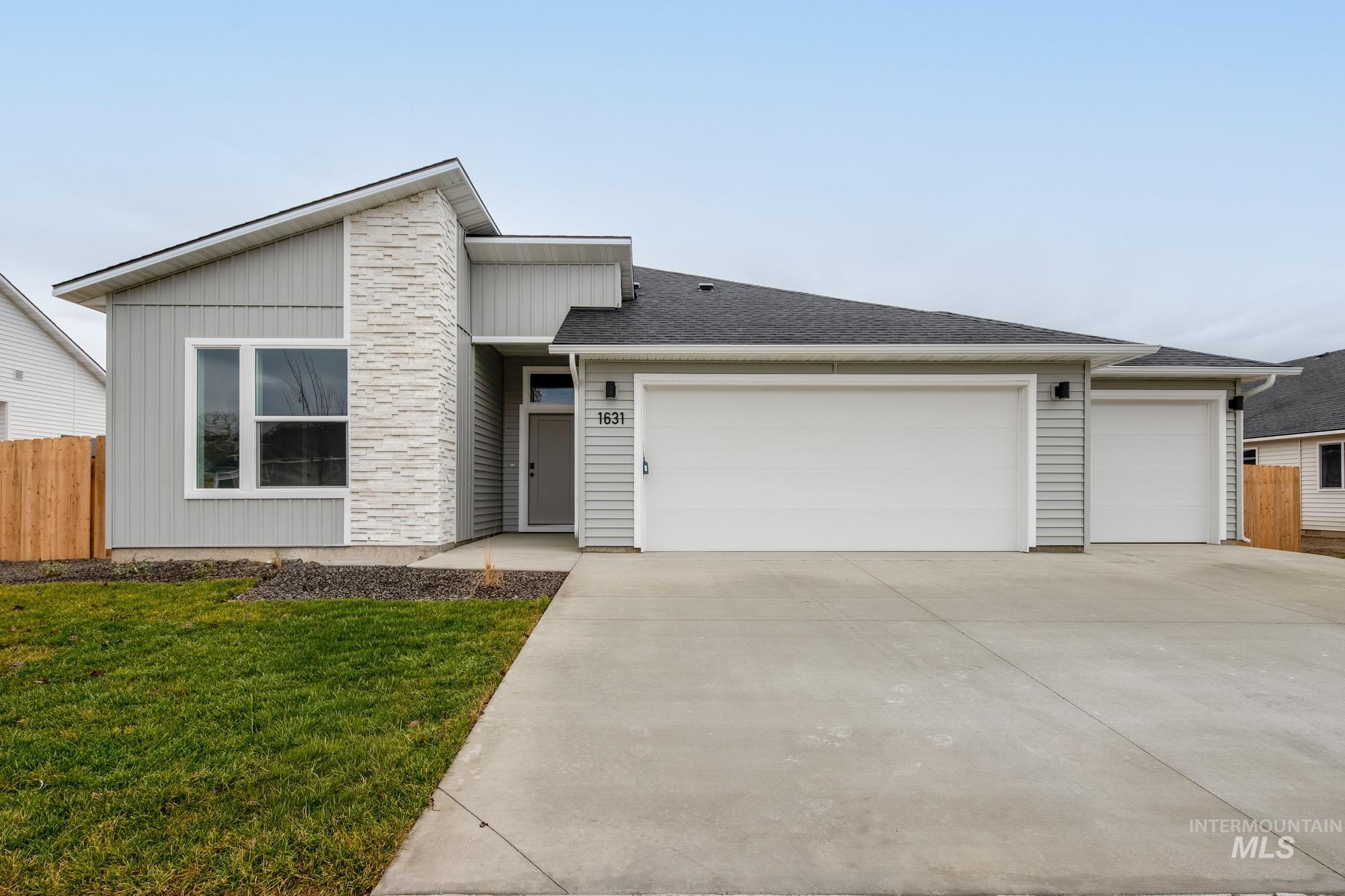 View of front of property featuring driveway, an attached garage, and a shingled roof