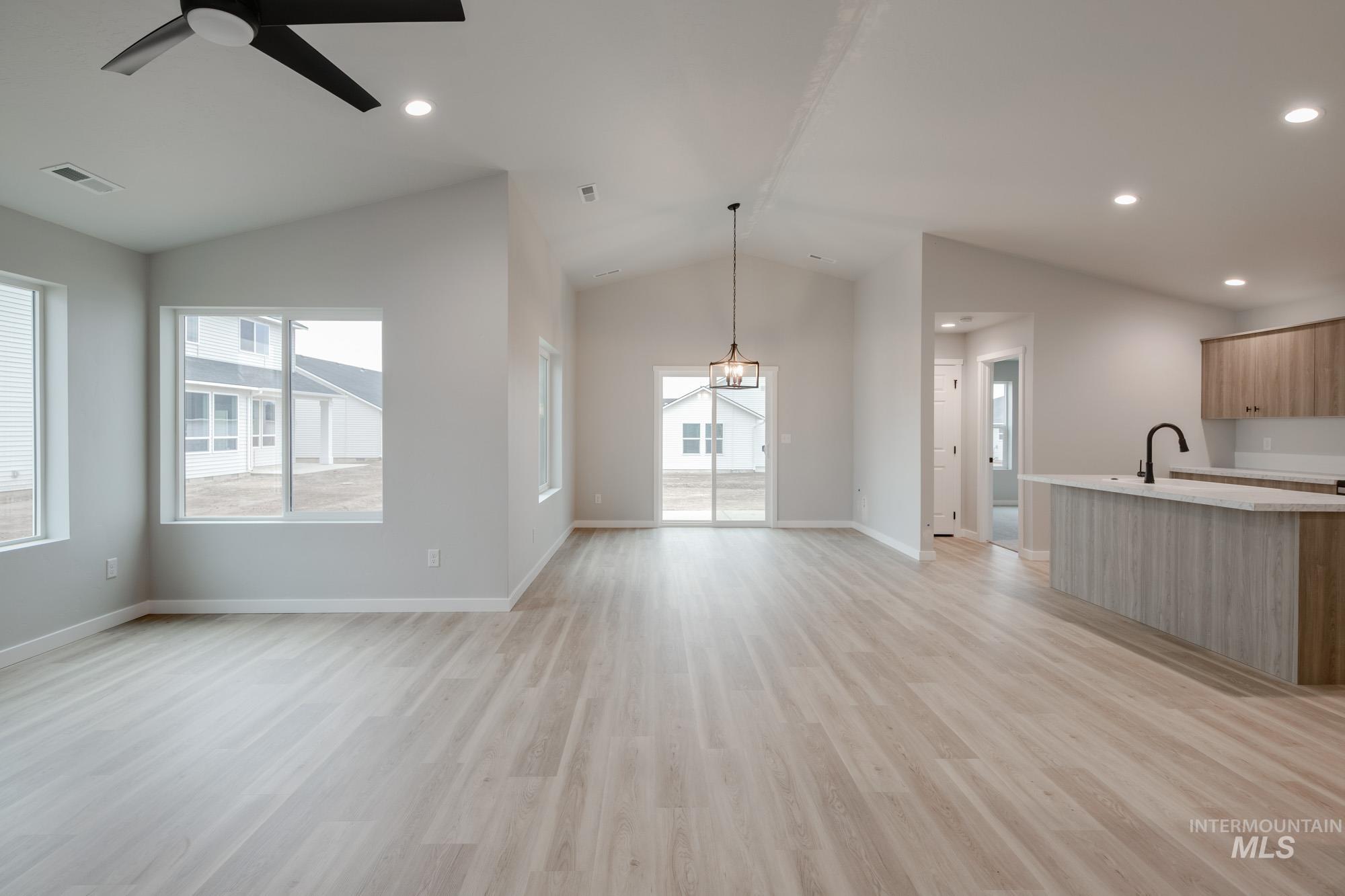 1631 Long Pond Street Middleton, ID 83644 - Photo 11 of 22 Unfurnished living room featuring vaulted ceiling, light wood-type flooring, ceiling fan, a chandelier, and recessed lighting