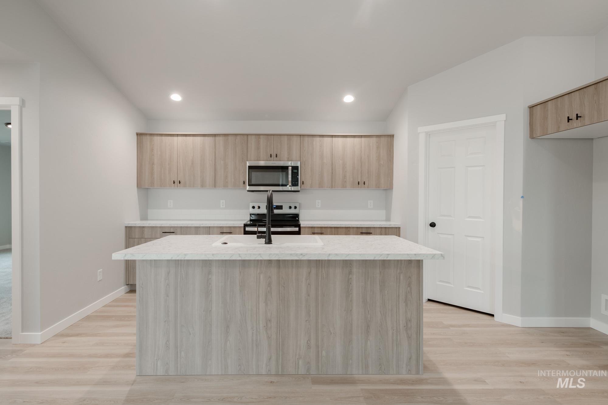 1631 Long Pond Street Middleton, ID 83644 - Photo 4 of 22 Kitchen with light brown cabinets, stainless steel appliances, a center island with sink, light wood-style floors, and modern cabinets
