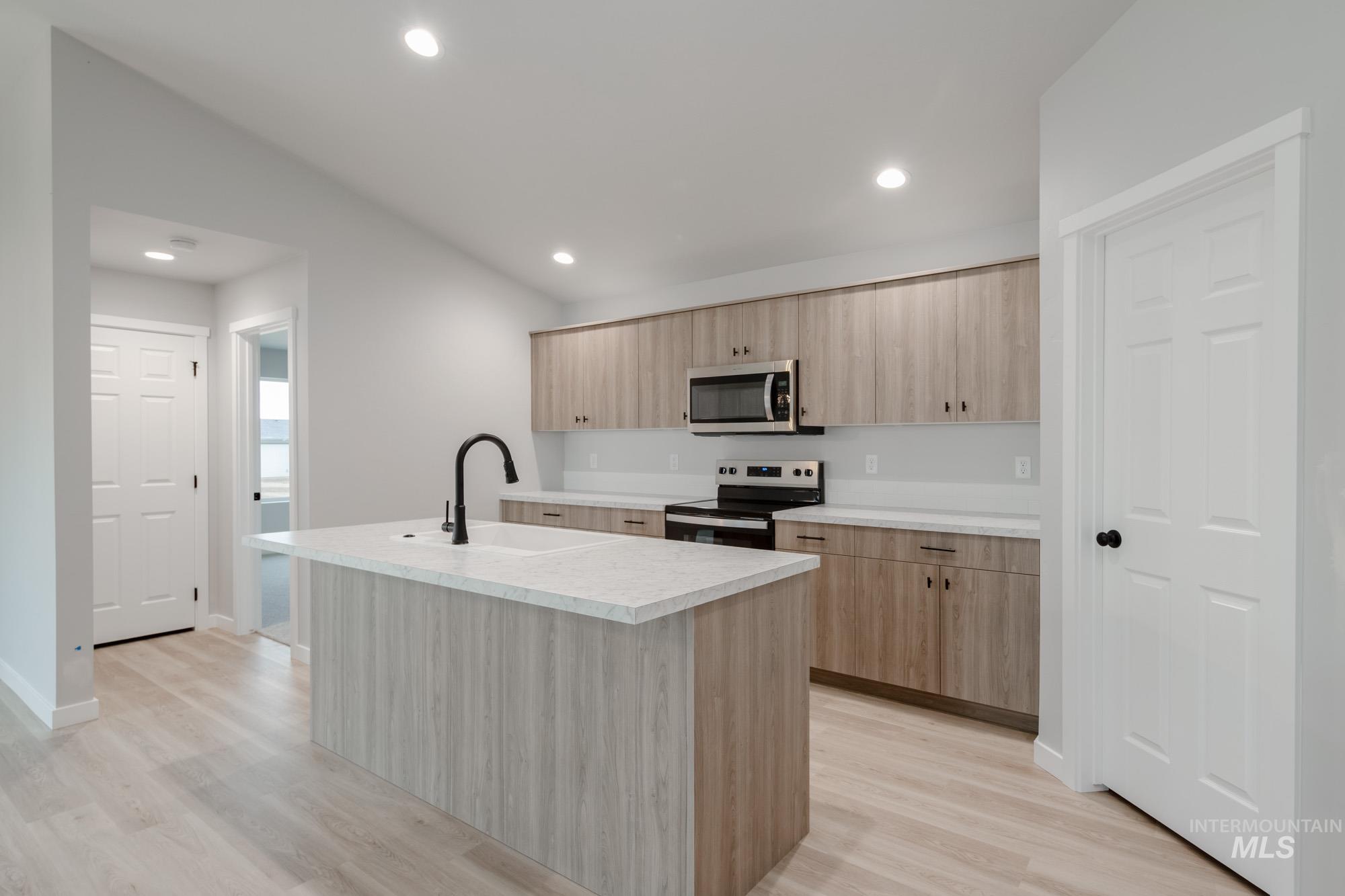 1631 Long Pond Street Middleton, ID 83644 - Photo 8 of 22 Kitchen featuring appliances with stainless steel finishes, a kitchen island with sink, light wood finished floors, light brown cabinets, and recessed lighting