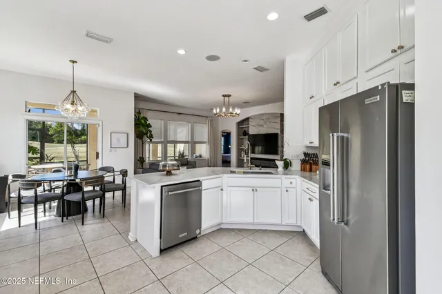 a kitchen with stainless steel appliances granite countertop a refrigerator a stove a sink a dining table and chairs with wooden floor