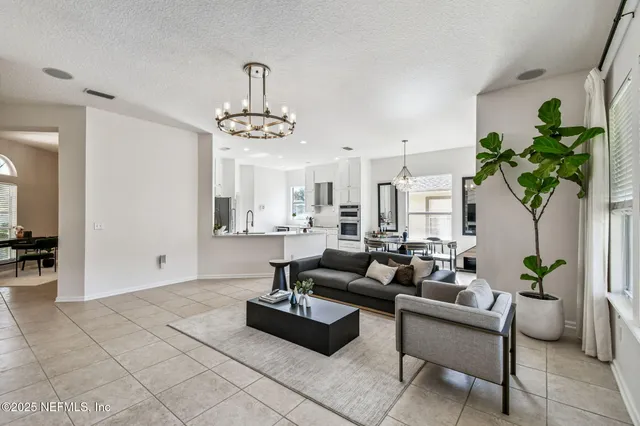 a living room with furniture a chandelier and a dining table