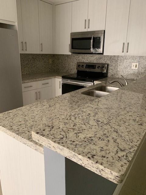 1950 Southwest 121st Court, Unit 240 Miami, FL 33175 - Photo 12 of 27 a kitchen with granite countertop a sink a stove and a microwave