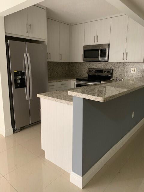 1950 Southwest 121st Court, Unit 240 Miami, FL 33175 - Photo 2 of 27 a kitchen with stainless steel appliances a refrigerator a stove a microwave and cabinets