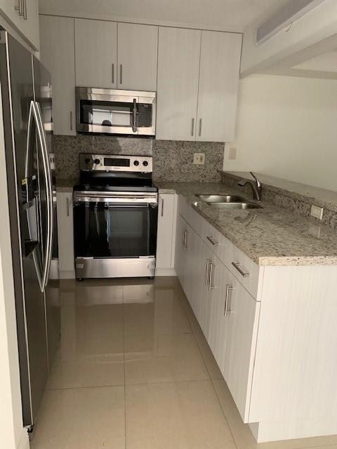 1950 Southwest 121st Court, Unit 240 Miami, FL 33175 - Photo 3 of 27 a kitchen with stainless steel appliances granite countertop a stove a refrigerator and a sink