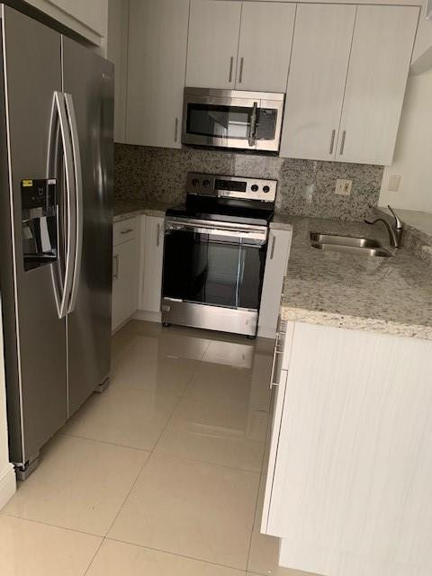 1950 Southwest 121st Court, Unit 240 Miami, FL 33175 - Photo 4 of 27 a kitchen with stainless steel appliances granite countertop a refrigerator a stove and a sink with granite countertops