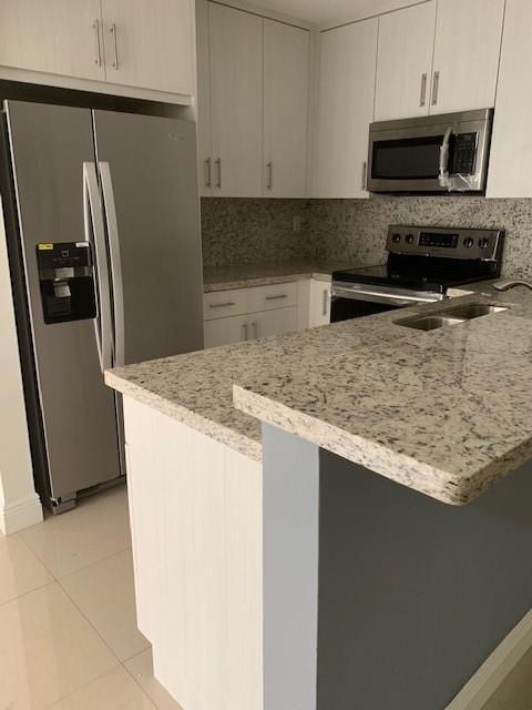 1950 Southwest 121st Court, Unit 240 Miami, FL 33175 - Photo 5 of 27 a kitchen with stainless steel appliances granite countertop a refrigerator a stove top oven a sink and dishwasher
